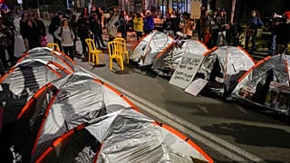 Familiares de rehenes israelíes y otros manifestantes bloquean una carretera con tiendas de campaña durante una protesta por fuera de la residencia de Netanyahu en Jerusalén