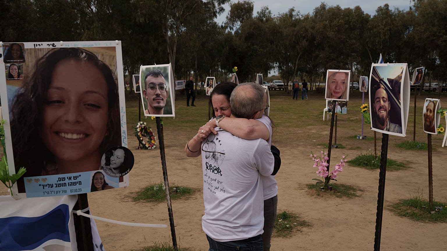 Ela Bahat embraces her husband Idan as they stand next to a picture of their 30-year-old son Dror, right, who was killed on Oct. 7 at the Nova music festival.