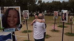 Ela Bahat embraces her husband Idan as they stand next to a picture of their 30-year-old son Dror, right, who was killed on Oct. 7 at the Nova music festival.