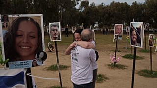 Ela Bahat embraces her husband Idan as they stand next to a picture of their 30-year-old son Dror, right, who was killed on Oct. 7 at the Nova music festival.