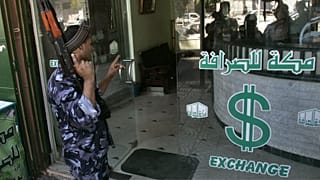 عکس تزئینی از یک پلیس فلسطینی در مقابل یک صرافی در نوار غزه در سال ۲۰۰۶