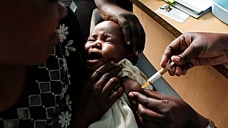 A mother holds her baby receiving a new malaria vaccine as part of a trial in Kenya.