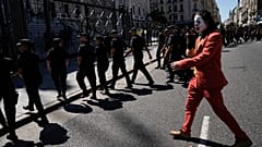A protester in a Joker costume walks behind police leaving the area near Congress at the end of a protest during a national strike in Buenos Aires, 
