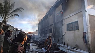 فلسطيني يحاول إخماد الحرائق التي اندلعت في مبنى تابعة للأونروا
