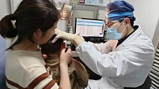 Dr Yilai Shu examines a young patient at the Eye & ENT Hospital of Fudan University in Shanghai, China, after a gene therapy procedure for hereditary deafness.