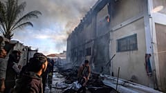 فلسطينيون يحاولون إطفاء حريق في مبنى تابع للأونروا يستخدمه النازحون كملجأ، بعد استهدافه بقذيفة دبابة إسرائيلية في خان يونس. 2024/01/24