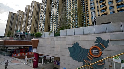 A man walks by a China's map showing Evergrande development projects and its apartment buildings are seen behind, at an Evergrande city plaza in Beijing, 15 Sept. 2021.