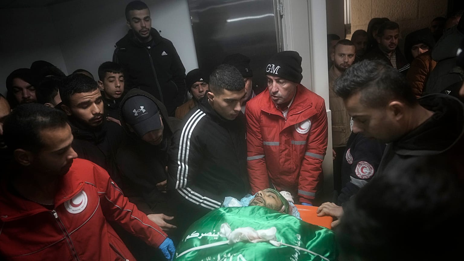 Palestinians gather around the body of Muhammad Jalamneh, draped in the Hamas militant group flag, in the morgue of Ibn Sina Hospital after he was killed.
