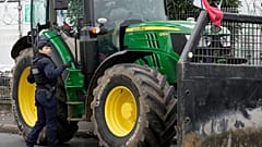Un agente di polizia parla con un agricoltore fuori dal mercato internazionale di Rungis, alla periferia di Parigi
