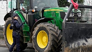 Un agente di polizia parla con un agricoltore fuori dal mercato internazionale di Rungis, alla periferia di Parigi
