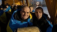 Recently swapped Ukrainian prisoners of war covered in national flags sit in a bus after a prisoner exchange on the Ukrainian Russian border, on Wednesday, Jan. 31, 2024.