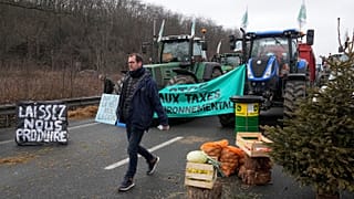 Un agricoltore passa davanti alle scorte su un'autostrada bloccata ad Argenteuil, a nord di Parigi (1 febbraio 2024)