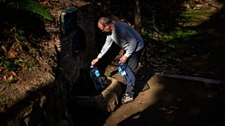 Joan Torrent, 64 ans, remplit des bidons en plastique à une source naturelle à Gualba.