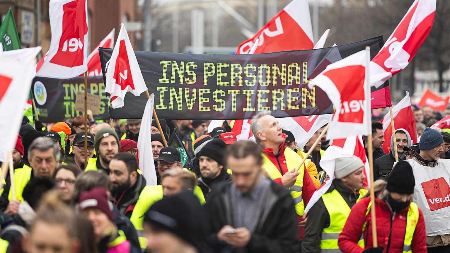 Los participantes en una manifestación de Verdi caminan por el centro de la ciudad de Hannover, Alemania, el 2 de febrero de 2024. La pancarta dice "Invertir en personal".