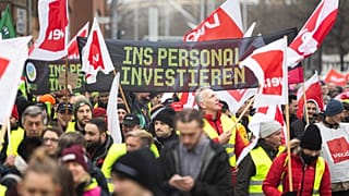 Los participantes en una manifestación de Verdi caminan por el centro de la ciudad de Hannover, Alemania, el 2 de febrero de 2024. La pancarta dice "Invertir en personal".