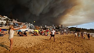 Rauchwolken über Urlaubern, die am Strand in Viña del Mar Paddelball spielen, 2. Februar 2024.