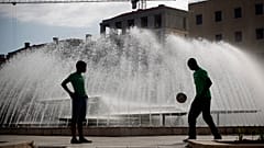 FILE. Two young men, seen in silhouette, play with a soccer ball at Lisbon's Martim Moniz