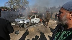 Ciudadanos palestinos observan cómo arde un coche tras ser alcanzado por un dron israelí en Rafah, en el sur de la Franja de Gaza, el domingo 4 de febrero de 2024.
