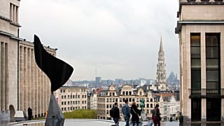 Gente paseando con equipaje con la ciudad de Bruselas como telón de fondo