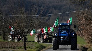 Manuele Calzoni, en el centro, conduce su tractor para unirse a la protesta de otros agricultores cerca del cruce de carreteras, en Orte, Italia, el sábado 3 de febrero de 202