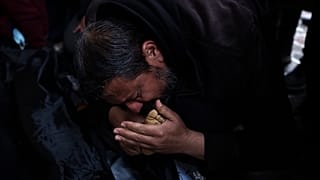 فلسطيني يقبل قدم طفله الذي قتل في الغارة الإسرائيلية