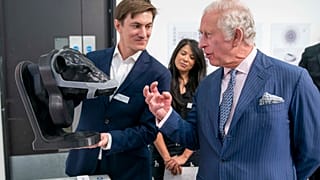 Britain's King Charles looks at a wearable device for cattle to neutralise their methane emissions in real time created by design group Zelp.