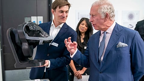 Britain's King Charles looks at a wearable device for cattle to neutralise their methane emissions in real time created by design group Zelp.