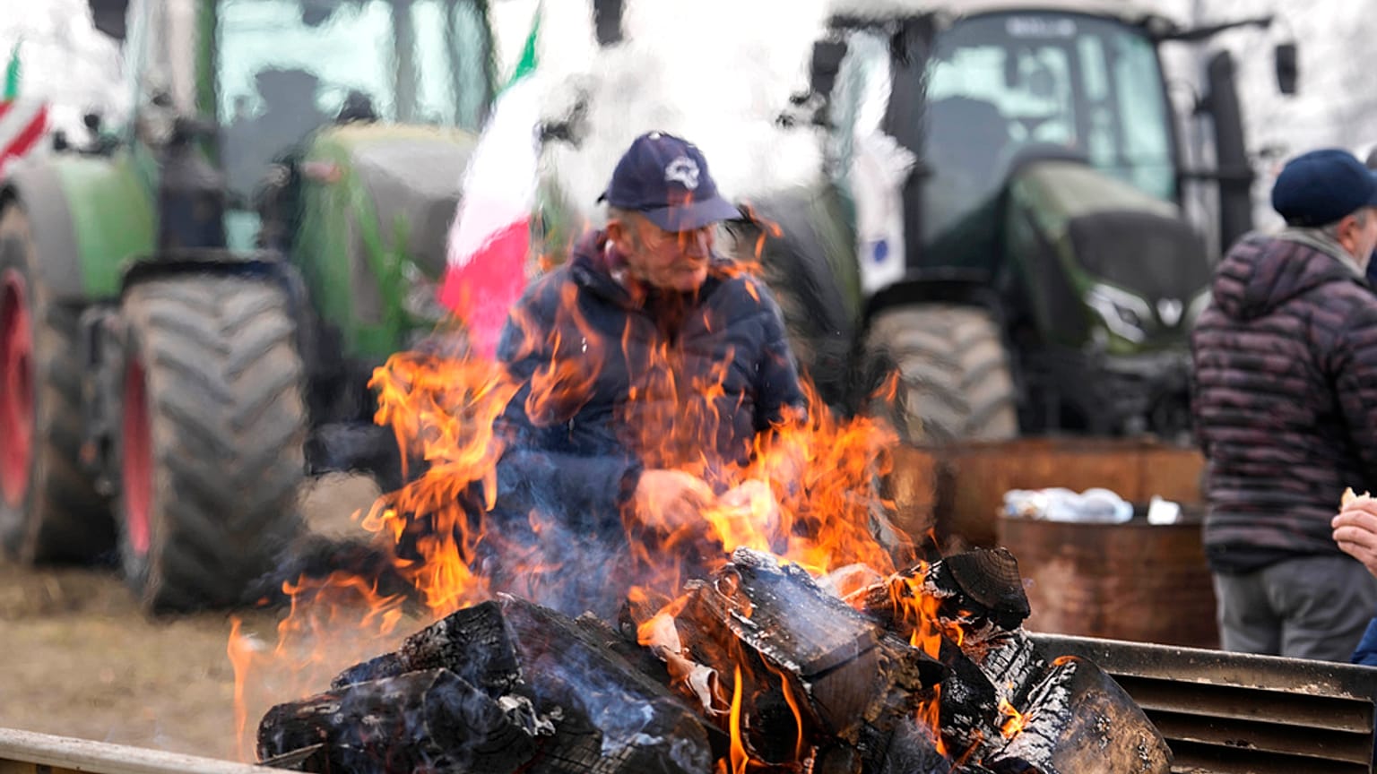 A farmer sits next to a fire during a gathering near the highway junction in Melegnano, near Milan, Italy, Wednesday, 7 February, 2024.