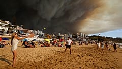Vacacionistas juegan a la pelota en la playa con el cielo oscurecido por el humo de los incendios forestales en Viña del Mar, Chile.