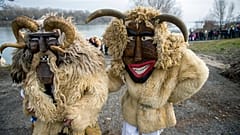 Hombres con disfraces y máscaras llegan desde una isla al otro lado del río Danubio en Mohács, Hungría, para participar en el tradicional desfile de carnaval de la ciudad.