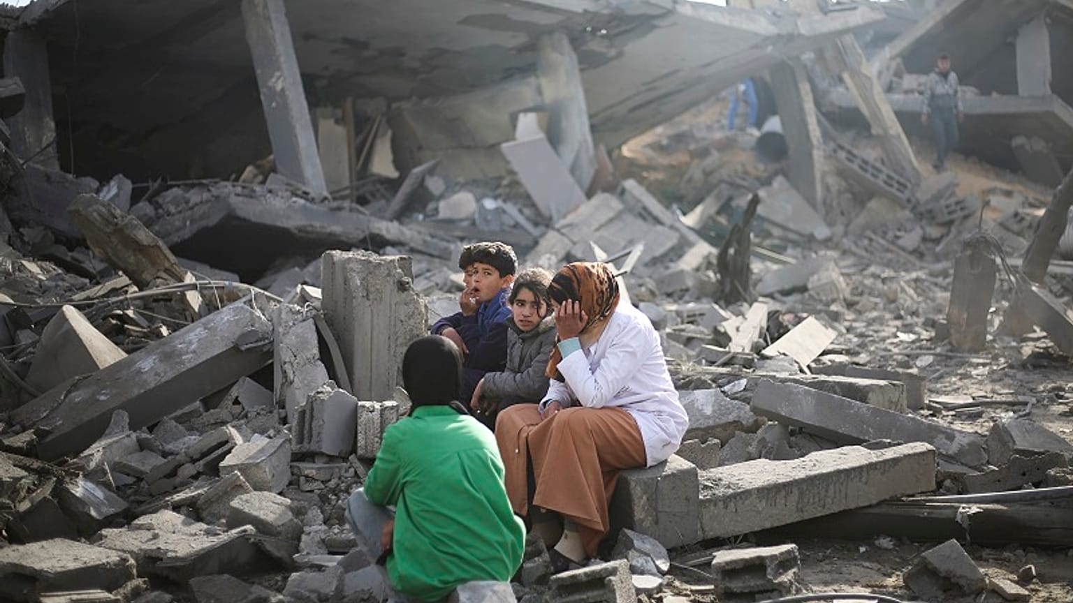 Los palestinos sentados junto a la destrucción causada por el bombardeo israelí de la Franja de Gaza en Rafah el lunes 12 de febrero de 2024.