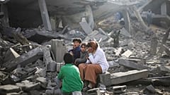 Los palestinos sentados junto a la destrucción causada por el bombardeo israelí de la Franja de Gaza en Rafah el lunes 12 de febrero de 2024.