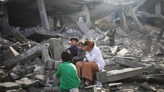 Los palestinos sentados junto a la destrucción causada por el bombardeo israelí de la Franja de Gaza en Rafah el lunes 12 de febrero de 2024.