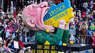 "Подавись!" - президент России Владимир Путин, пожирающий Украину, на карнавальном параде в Дюссельдорфе, 12 февраля 2024 г.