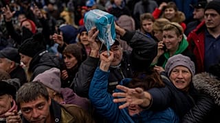 Жители, собравшиеся у пункта раздачи помощи, получают грузы в центре Херсона, южная Украина.