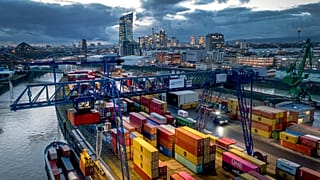 A container is loaded onto a cargo ship in the harbor in Frankfurt, Germany, Wednesday, Dec. 13, 2023. In background the European Central Bank. (AP Photo/Michael Probst)