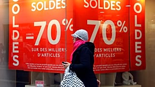 A woman walks past a store advertising for winter sales in Marseille, southern France, Thursday, Jan. 7, 2016