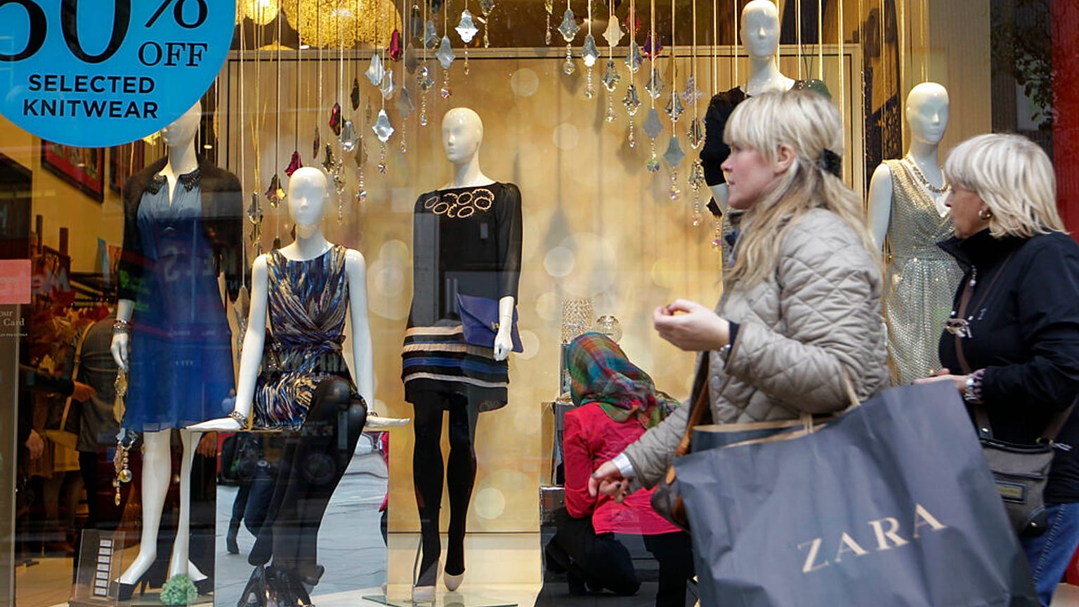 Shoppers walk by a shop in central London, Thursday, Nov. 17, 2011. 