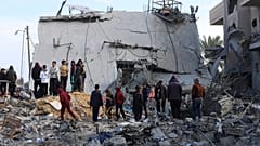 فلسطينيون ينظرون إلى الدمار الذي خلفته غارة إسرائيلية على مبنى سكني في رفح