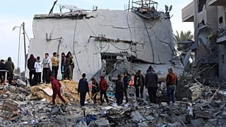 فلسطينيون ينظرون إلى الدمار الذي خلفته غارة إسرائيلية على مبنى سكني في رفح