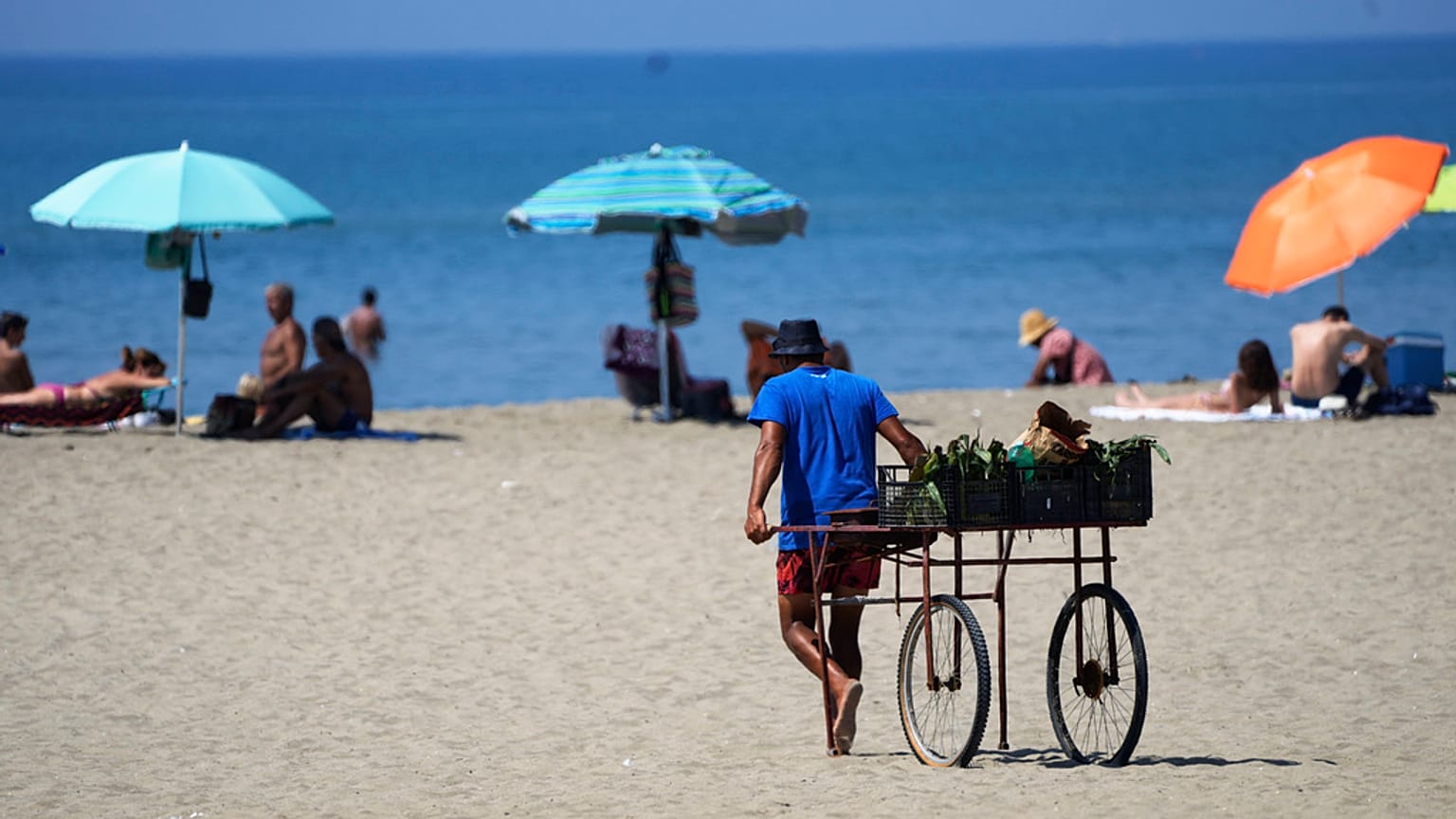 Un vendedor playero tira de su carruaje en una playa de Ostia, cerca de Roma, el miércoles 23 de agosto de 2023.