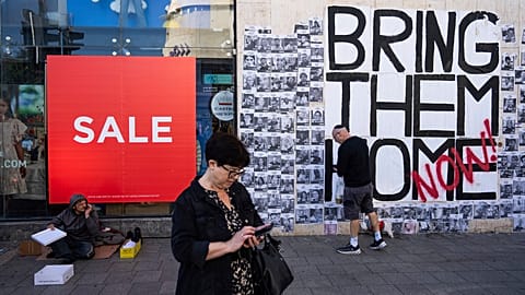People walk past a wall with photographs of hostages, mostly Israeli civilians who were abducted during the Oct. 7, unprecedented Hamas attack on Israel, in Tel Aviv, Israel.