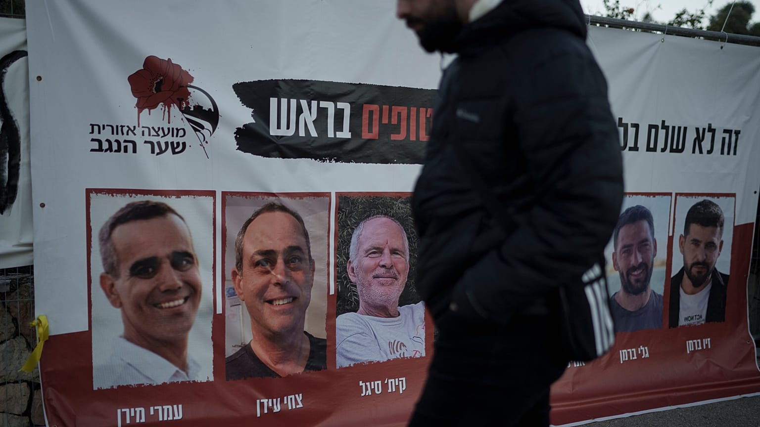 A man in Jerusalem walks past a banner with photographs of hostages who were abducted during Hamas's 7 October attack on southern Israel.