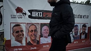 A man in Jerusalem walks past a banner with photographs of hostages who were abducted during Hamas's 7 October attack on southern Israel.