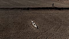 Ein Mann geht an einem verlassenen Kanu am Sau-Stausee vorbei.