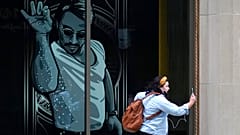 A passer-by uses a mobile device near a window featuring a likeness of chef and social media star Salt Bae outside the Nusr-Et Boston restaurant, Sept. 29, 2020.