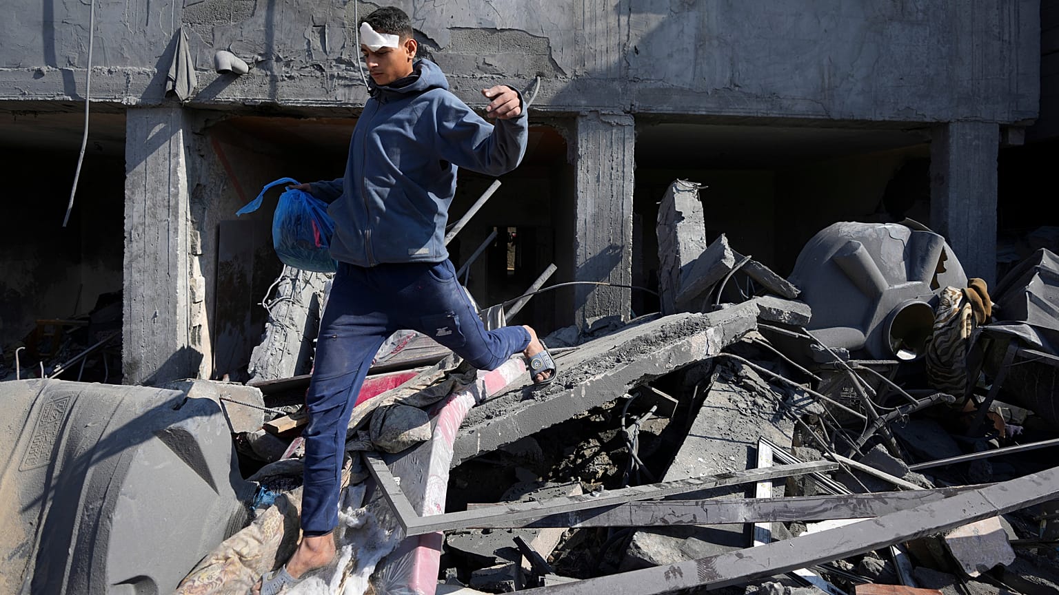 شاب فلسطيني يمشي فوق أنقاض منزل عائلة في دير البلح دمره القصف الإسرائيلي على غزة
