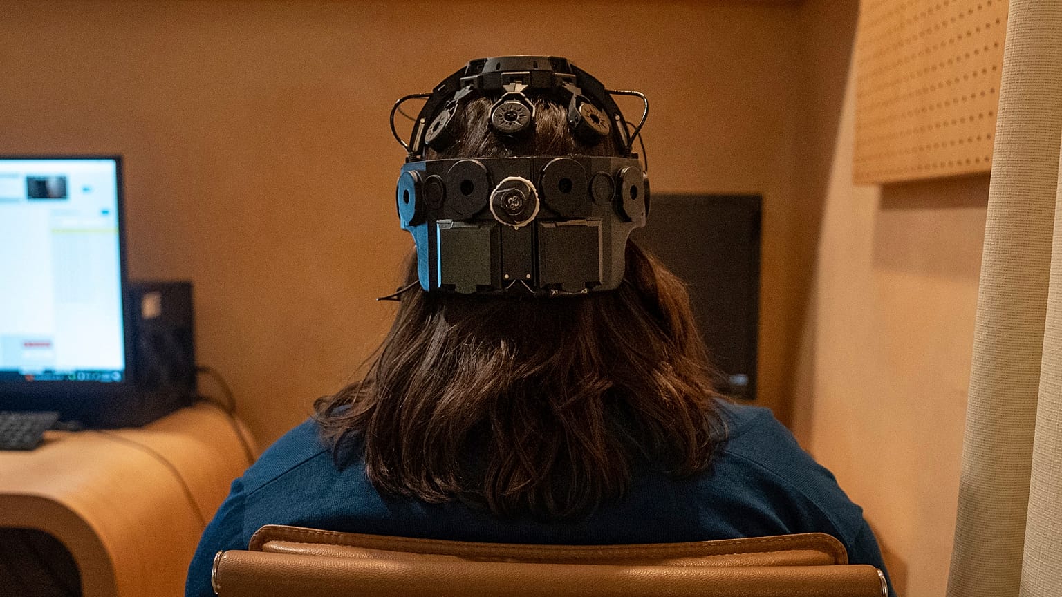 Emily Hollenbeck, a deep brain stimulation therapy patient, demonstrates an EEG device that records brain activity.