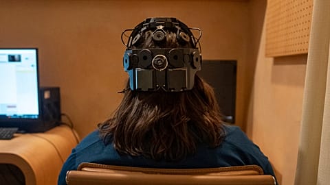 Emily Hollenbeck, a deep brain stimulation therapy patient, demonstrates an EEG device that records brain activity.