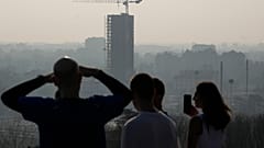 Los atletas se toman un descanso mientras corren en la colina de San Siro y contemplan el horizonte de Milán, Italia, el martes 20 de febrero de 2024.